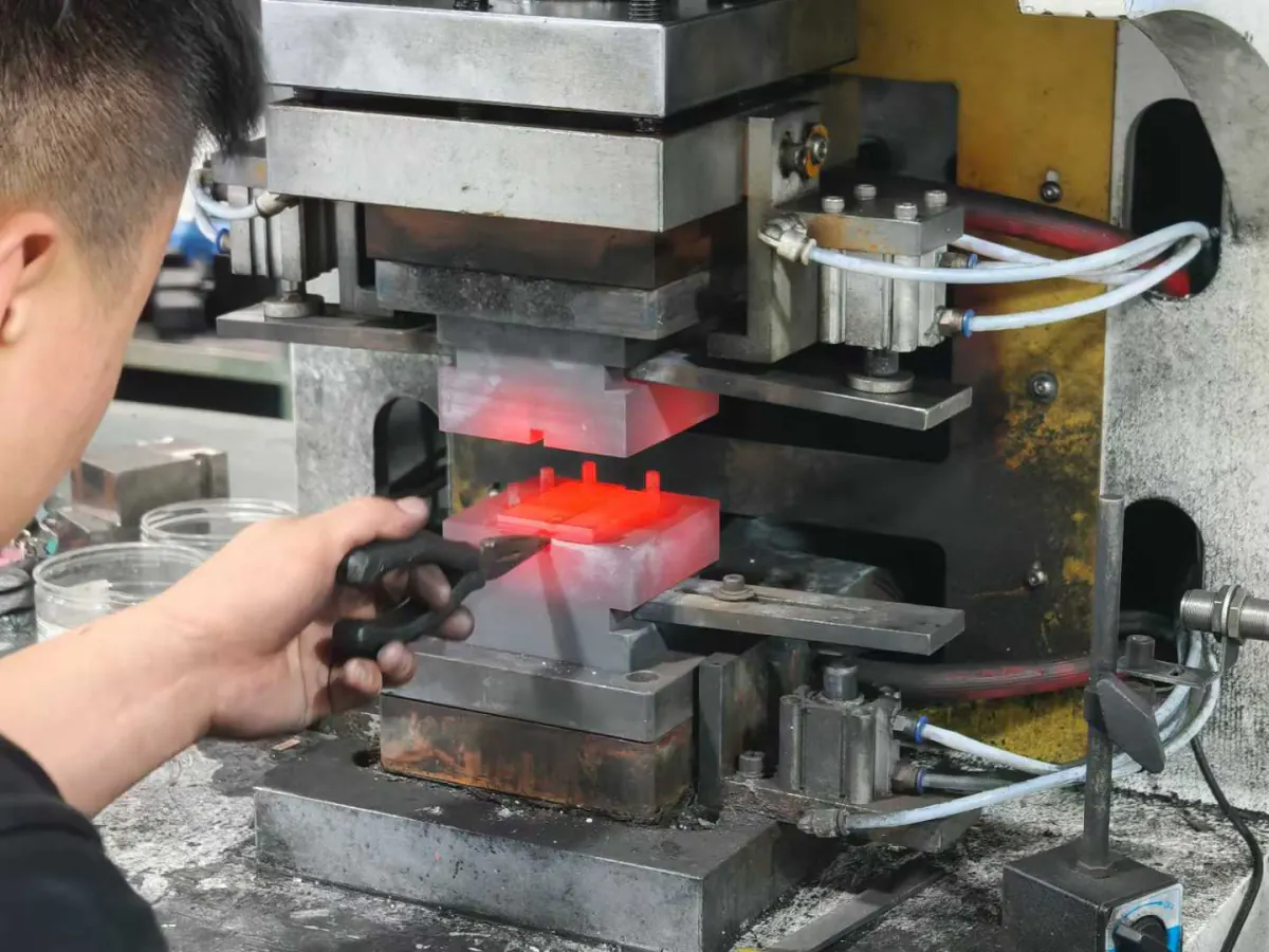 Operator forming a heated copper busbar blank in a press tool