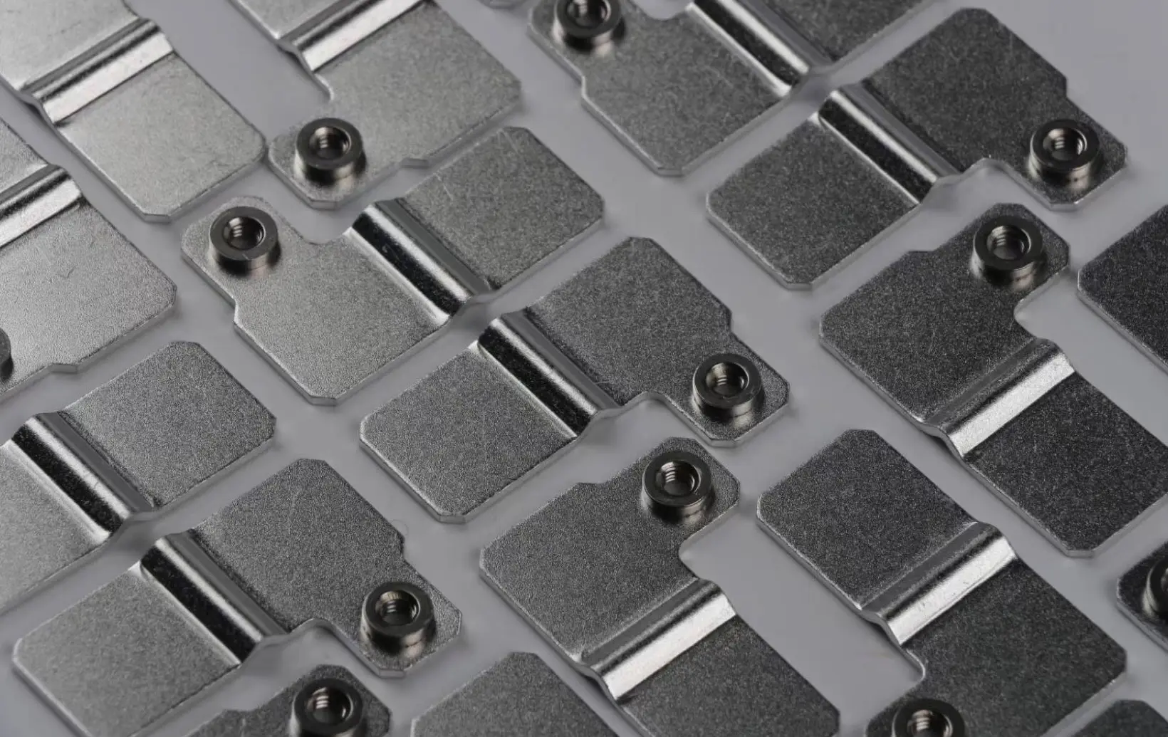 Nickel-plated stamped busbar terminals with pressed threaded inserts arranged in a carrier tray